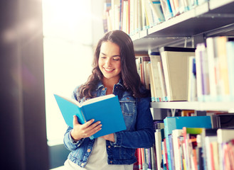 Wall Mural - education, high school, university, learning and people concept - smiling student girl reading book at library