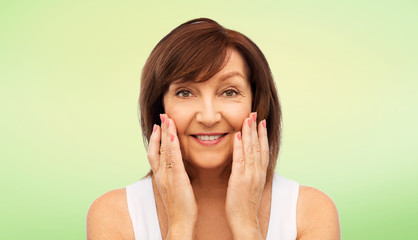 Sticker - beauty, skin care and old people concept - portrait of smiling senior woman touching her face over lime green background