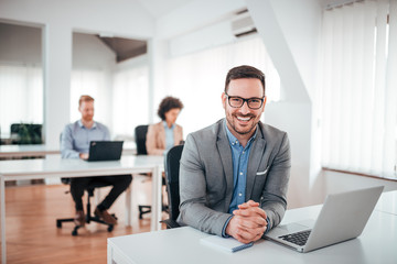 Portrait of young man sitting at his desk in the office.