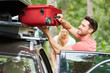 Mann packt Koffer in die Dachbox auf dem Auto