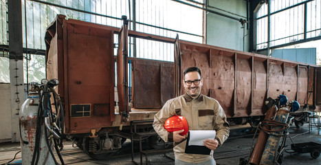 Wall Mural - Portrait of a smiling foreman at train factory.