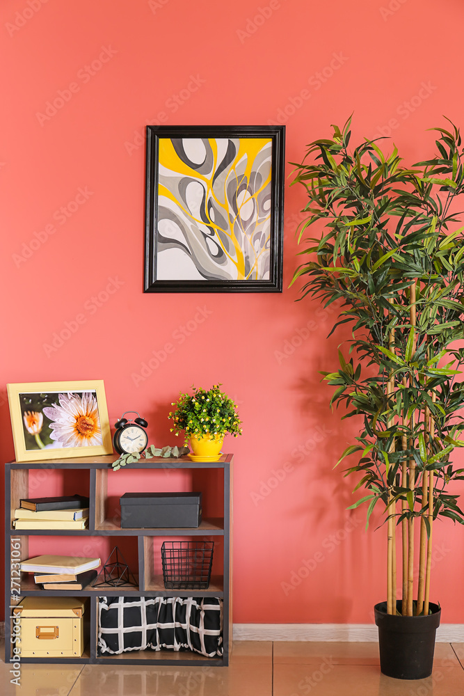 Shelving unit with decor and green plant near color wall