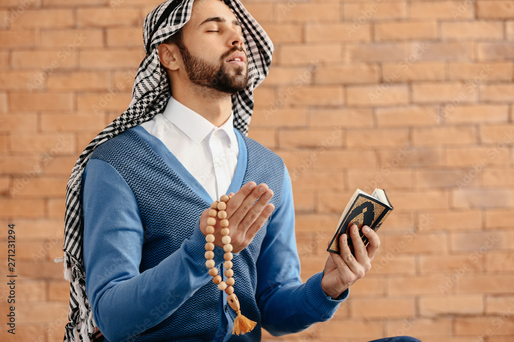 Young Muslim man praying indoors