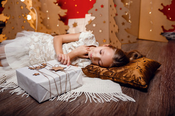 Beautiful little girl dreams of Christmas gifts.