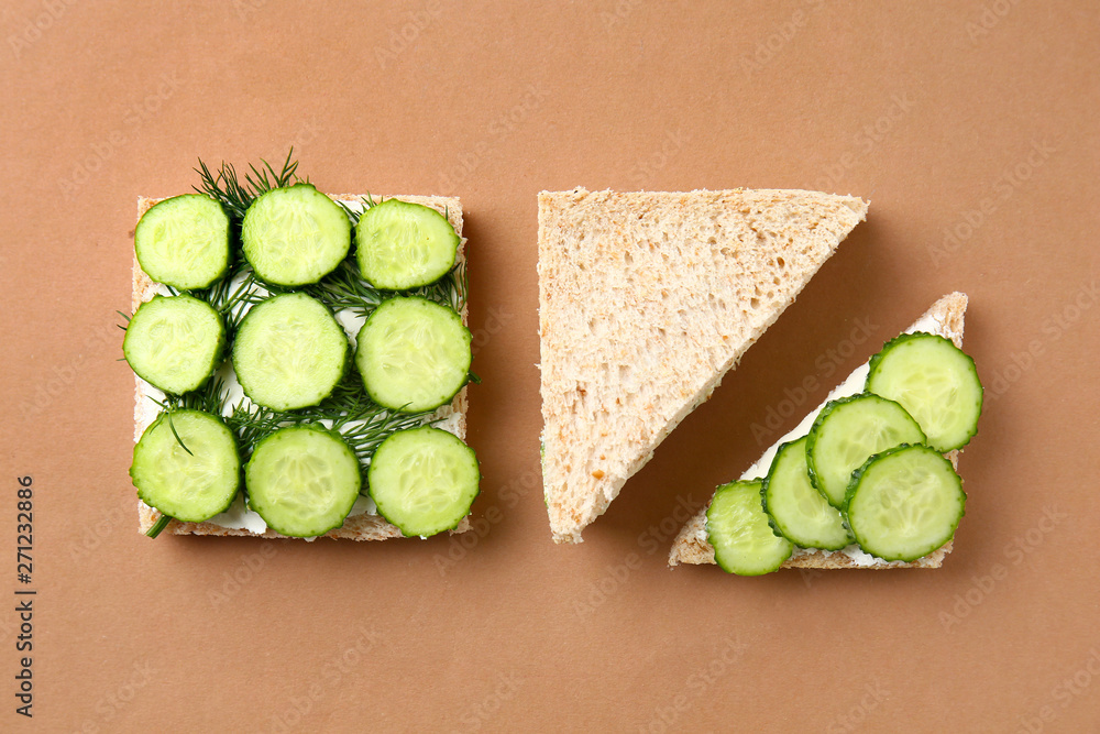 Tasty sandwiches with cucumber on color background