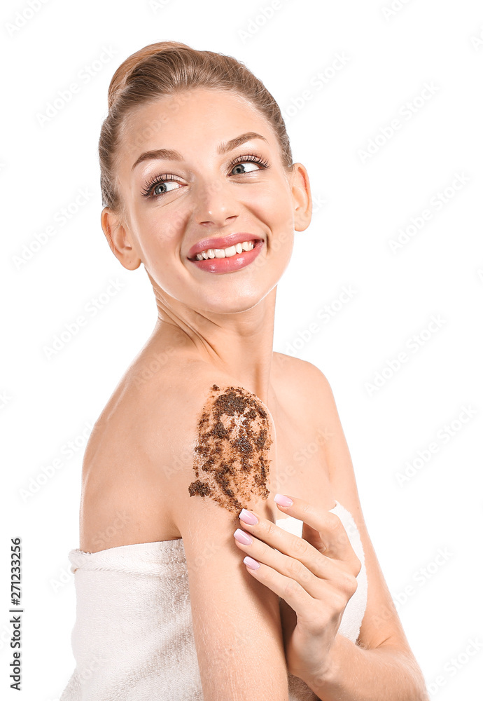 Young woman applying body scrub against white background