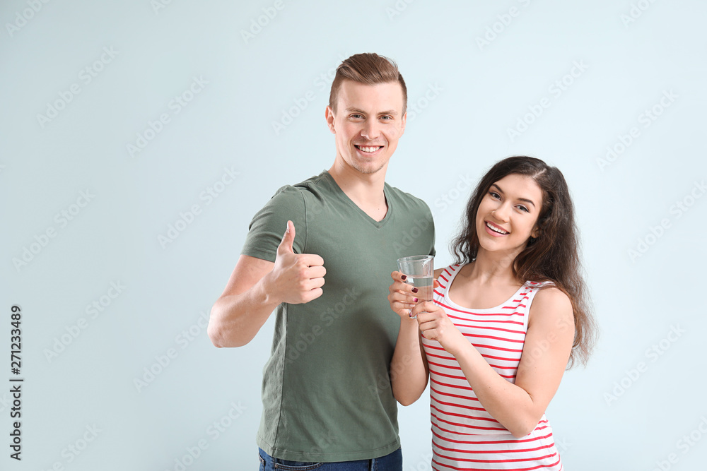 Young couple with glass of water on light background