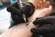 © Pixel-Shot - Professional artist making tattoo in salon, closeup