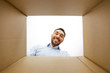 © Syda Productions - mail delivery and surprise concept - man looking into open parcel box, from below
