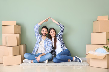 Sticker - Young couple with belongings sitting near color wall in their new house