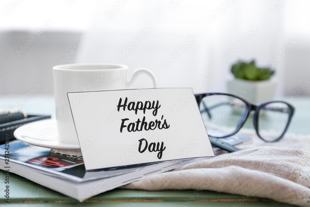 Cup of tea and greeting card for father on table