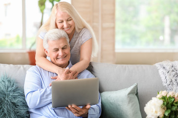 Canvas Print - Portrait of happy mature couple with laptop at home