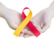 World hepatitis day concept. Red and yellow ribbon awareness on hand isolated on white background for against Hepatitis C and HIV/HCV Co-Infection with clipping path.