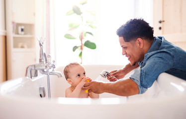 Wall Mural - Father washing small toddler son in a bathroom indoors at home.