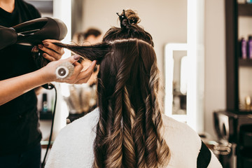 Beautiful brunette woman with long hair at the beauty salon getting a hair blowing. Hair salon styling concept.