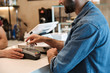 © Drobot Dean - Photo of smiling european man paying debit card in cafe while waiter holding payment terminal