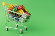 © Pavel - Christmas gifts in supermarket trolley on green background. Online shopping concept - trolley full of gifts. Black Friday and Cyber Monday