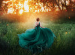 © kharchenkoirina - magical picture, girl with red hair runs into dark mysterious forest, lady in long elegant royal expensive emerald green turquoise dress with flying train, amazing transformation during fiery sunset