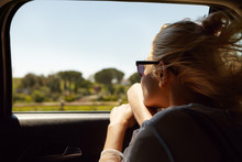 Back Shot Of Attractive Blonde European Woman Wearing Sunglasses Sitting Inside Car With Open Window, Enjoying Road Trip, Looking Out, Admiring Beautiful Summer Views. People And Lifestyle Concept