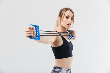 Image of athletic blond woman 20s dressed in sportswear stretching expander equipment during workout in gym