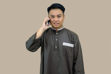 portrait of daytime Muslim youth posing in Muslim attire standing in front of the camera, looking attentive with a smile on the screen