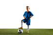 © master1305 - Young boy as a soccer or football player in sportwear standing with the ball like a winner, the best forward or goalkeeper on white background. Fit playing boy in action, movement, motion at game.