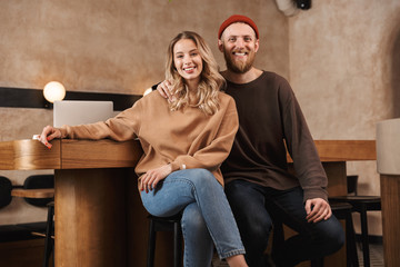 Happy young woman in cafe with computer on a table hugging.