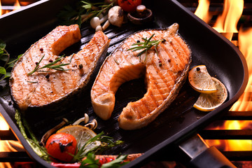 Wall Mural - Grilled salmon fish with various vegetables on pan on the flaming grill