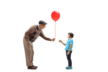 Wall Mural - Senior man giving a red balloon to a child