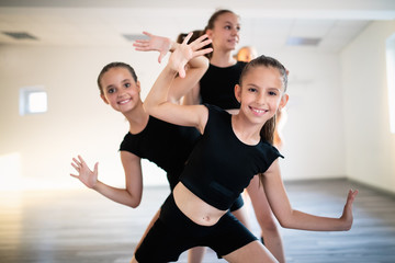 Group of fit happy children exercising dancing and ballet in studio together