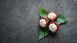 Mangosteen with a leaf on a black stone background. Tropical Fruits. Top view. Free space for text.