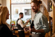 © Seventyfour - Waist up portrait of smiling young man consulting customer in liquor store, copy space