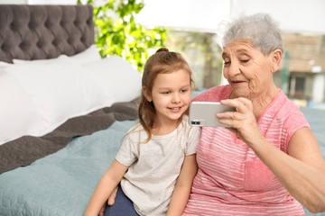 Canvas Print - Cute girl and her grandmother taking selfie  at home