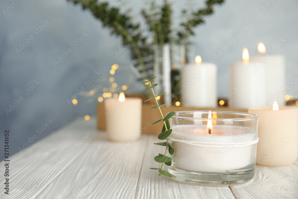Burning aromatic candle and eucalyptus branch on table. Space for text - obrazy, fototapety, plakaty 