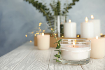 Canvas Print - Burning aromatic candle and eucalyptus branch on table. Space for text