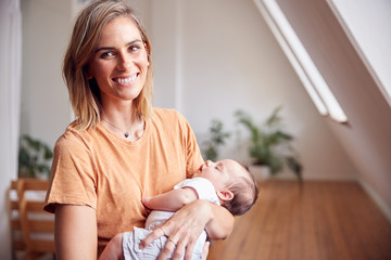 Wall Mural - Portrait Of Loving Mother Holding Newborn Baby At Home In Loft Apartment