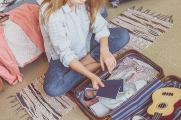 Wall Mural - Summer travel and vacation concept. Young woman packing suitcase at home