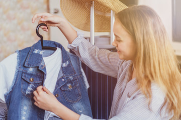 Wall Mural - Summer travel and vacation concept. Young woman packing suitcase at home