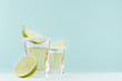 Alcohol cocktail - tequila with salty rim, piece lime in shot glasses in modern elegant pastel blue interior, copy space.