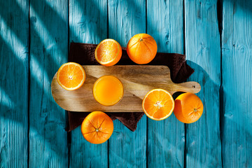 Wall Mural - Fresh orange fruits for juice on blue wooden board with shadow. Free space for your decoration and summer time. Healthy nutrition. 