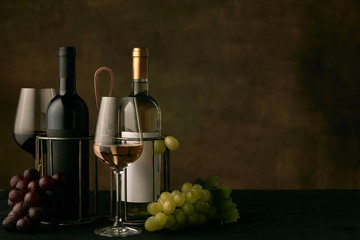 Wall Mural - Front view of tasty fruit plate of grapes with the wine bottles and glasses on dark studio background, copy space to insert your text or image. Gourmet food and drink.