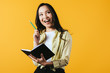 © LIGHTFIELD STUDIOS - smiling asian girl with notebook and pen, isolated on yellow