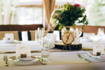 Beautiful decorated elegant wedding table for dinner with floral white bouquets, candlesticks and a white tablecloth glasses and porcelain plates