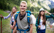 © NDABCREATIVITY - Group of happy friends with backpacks hiking together