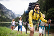 © NDABCREATIVITY - Group of happy friends with backpacks hiking together