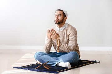 Wall Mural - Young Muslim man praying indoors