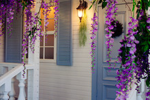 House Porch With A Lantern, Blue Door And Window And Wisteria Flowers Decoration