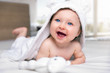 © moofushi - Happy six month old baby with a hooded towel lying on a bed and having fun