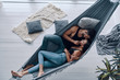 Loving everything about her. Top view of beautiful young couple embracing and smiling while resting in the hammock indoors