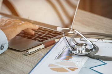 Wall Mural - Doctor working in hospital writing prescription clipboard, working an Laptop on desk in hospital with report analysis, Healthcare costs and fees in medical hostpital office